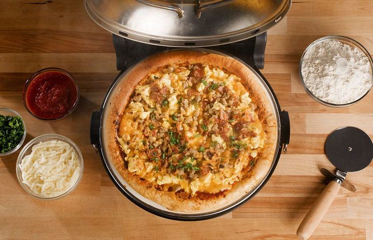 a pizza sitting on top of a wooden table next to other foods and condiments