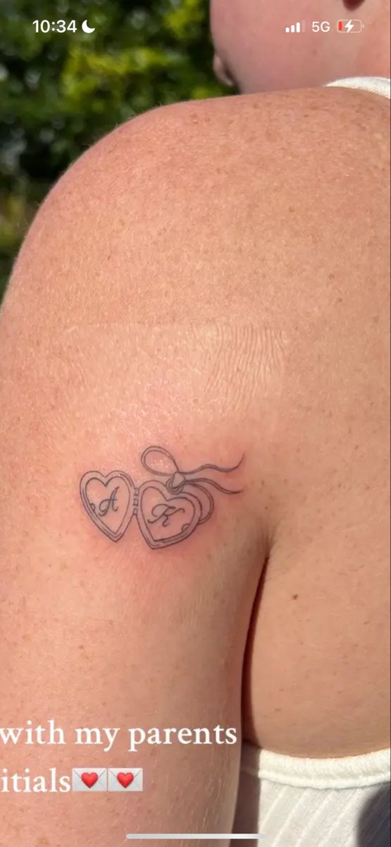 the back of a woman's shoulder with two hearts tattooed on her left side