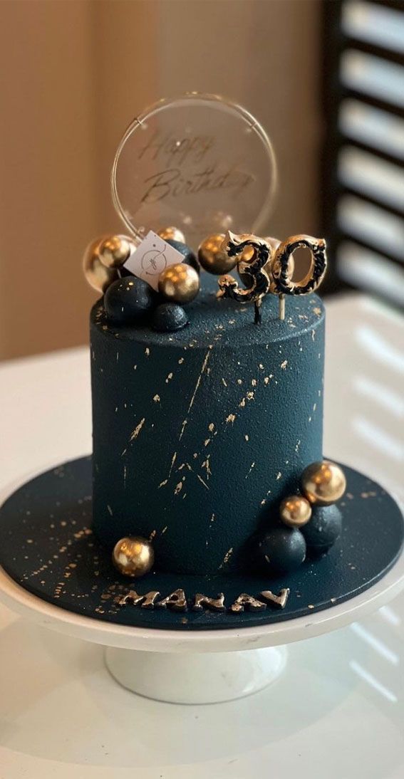 there is a blue cake with gold decorations on the top and bottom, sitting on a white plate