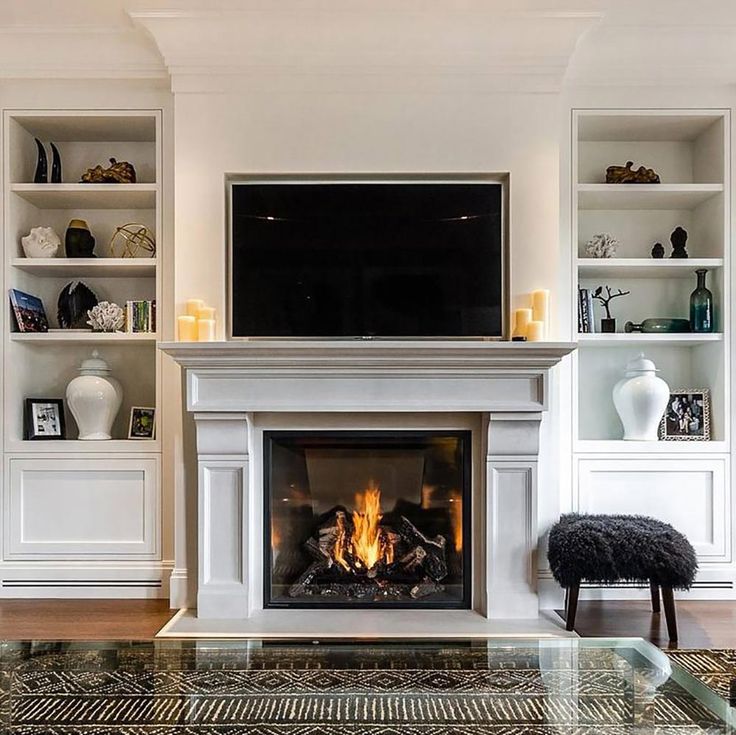 a living room with a fire place and bookshelves on either side of the fireplace