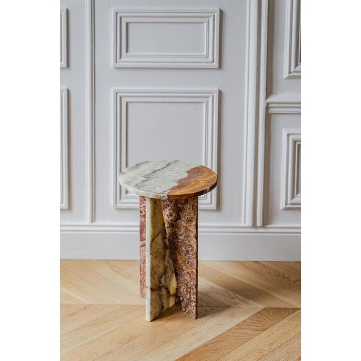 a small wooden table sitting on top of a hard wood floor next to a white wall