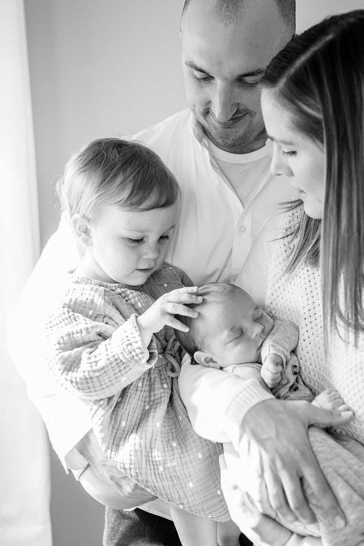 a black and white photo of a man holding a baby while two women hold him