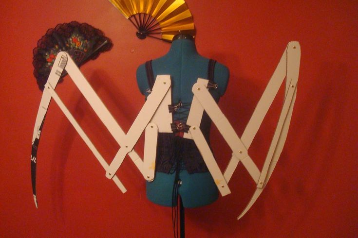 a mannequin is standing next to a fan and other items on a red wall