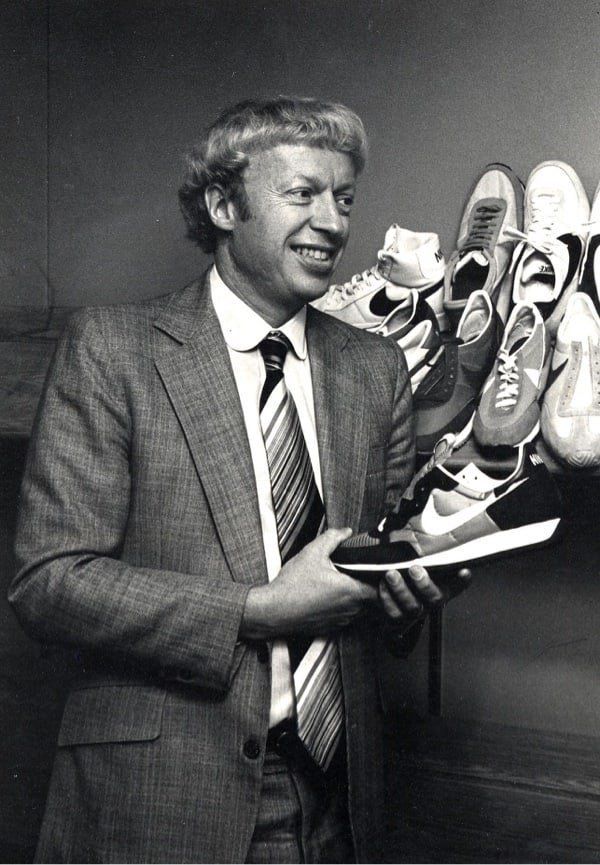 a man in a suit and tie holding up some shoes