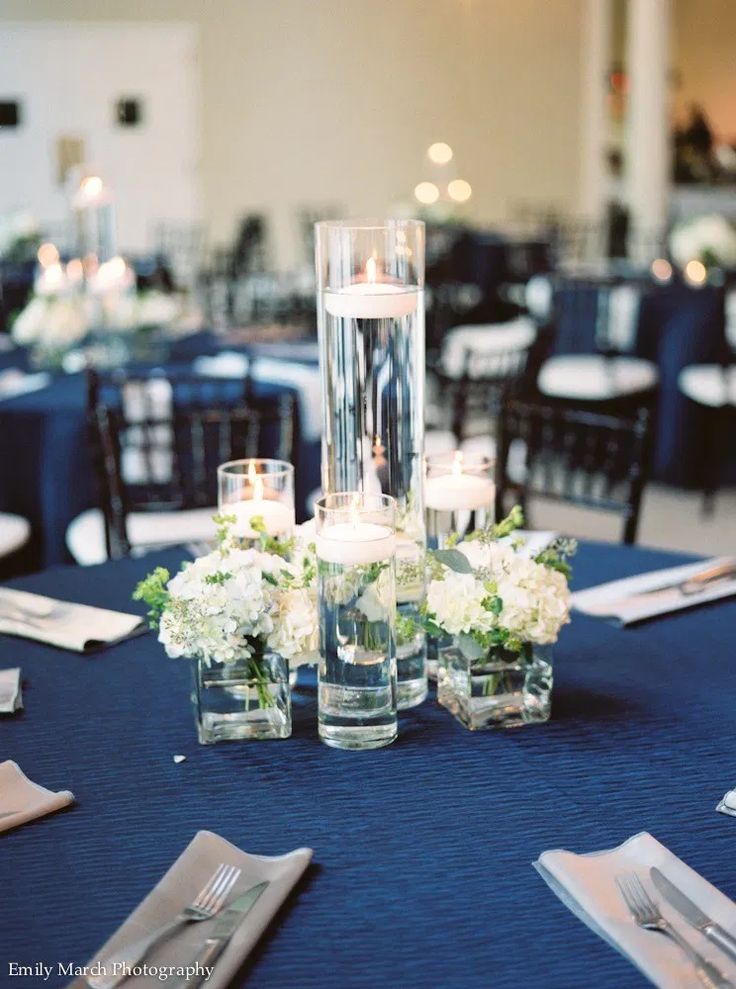 the centerpieces are arranged in clear vases with white flowers and greenery