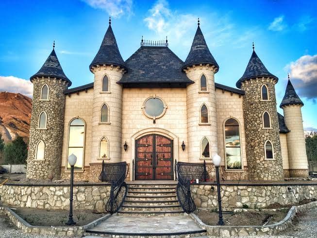 a large castle like building with turrets on it's roof and stairs leading up to the front door