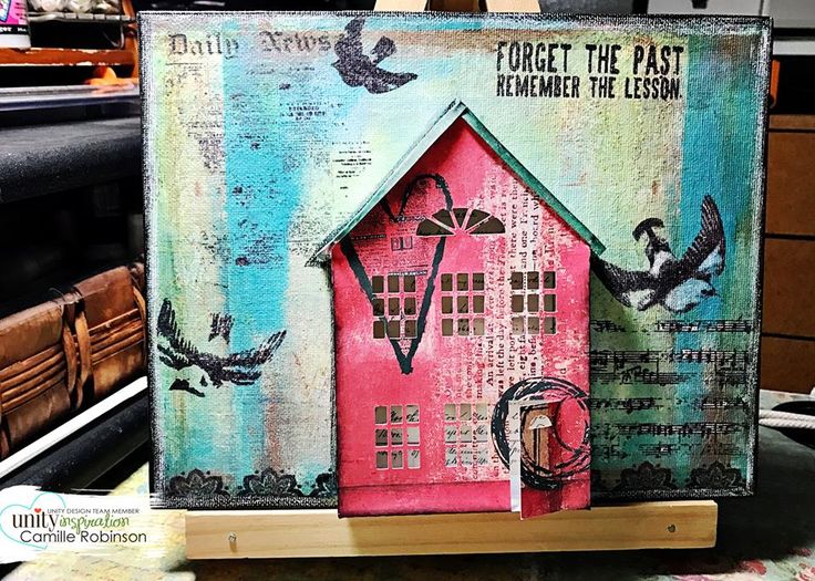 a painting with birds flying around it and a pink house on the top of a wooden block