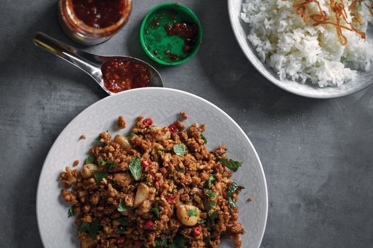 a plate with rice, meat and other food items on it next to two bowls