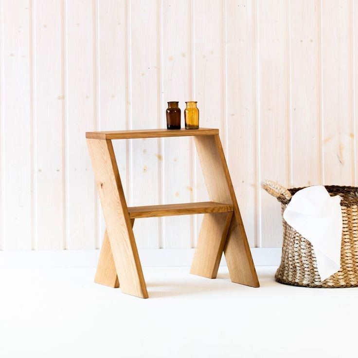 a wooden stool next to a basket with bottles on it and a white wall in the background