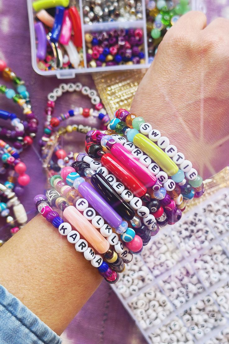 a woman's arm with several bracelets on it and beads in the background