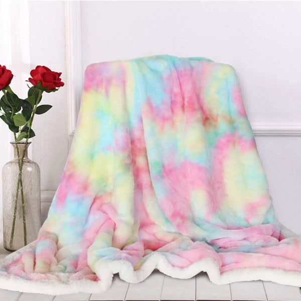 a pink and blue tie dye blanket sitting on top of a table next to flowers