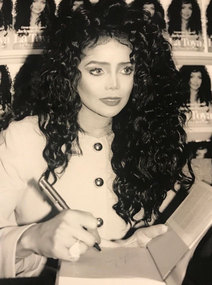 a black and white photo of a woman with curly hair holding a pen in her hand