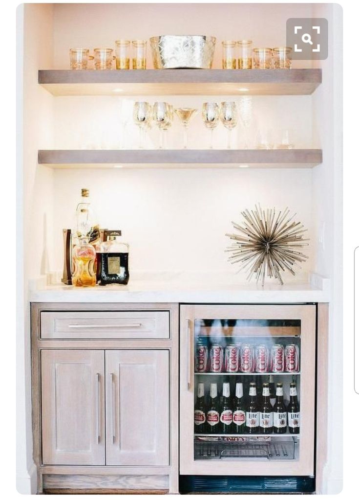 a beverage cooler sitting in the corner of a room with pictures on the wall above it