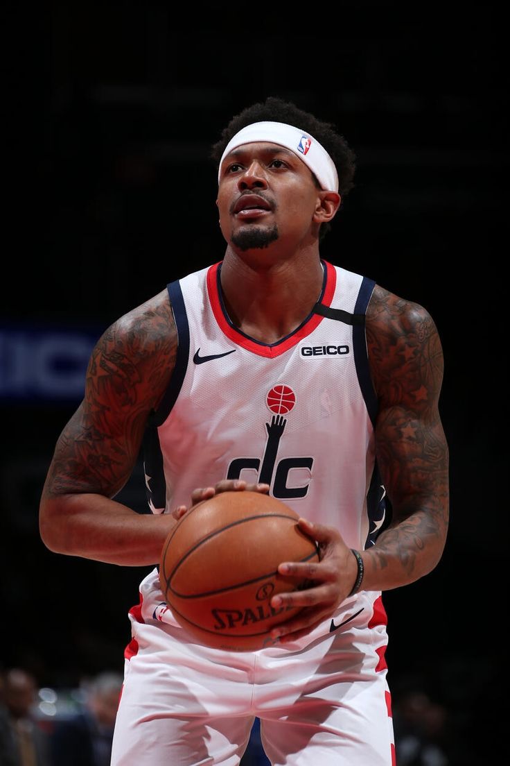 a man holding a basketball in his right hand and wearing a headband on top of it