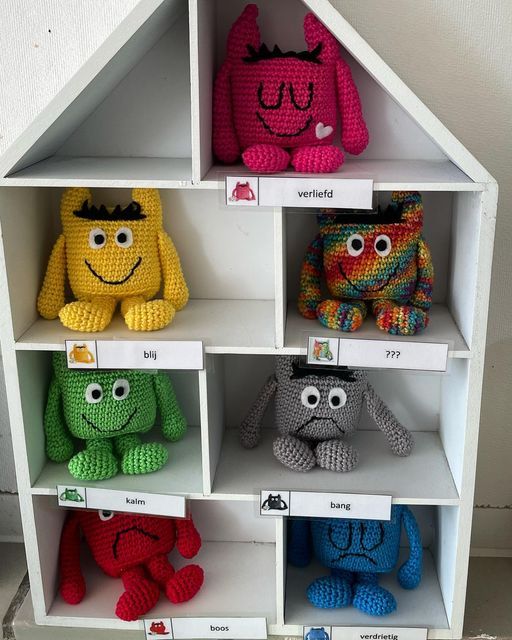 several crocheted stuffed animals are on display in a white shelving unit with numbered labels