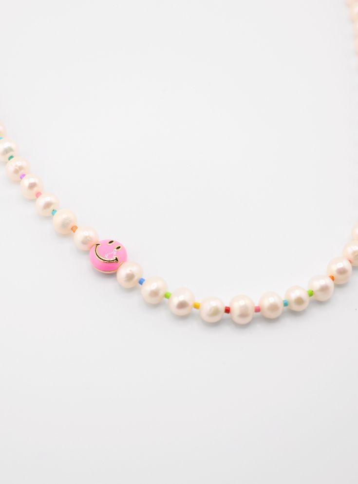 This necklace is designed to brighten your day and elevate your style with a touch of whimsy, making it a unique and unforgettable addition to your jewelry collection. The Smiley Pearl Necklace features a string of luminous pearls, meticulously selected for their timeless beauty and radiant quality. Nestled among these pearls is a captivating smiley face pendant, adding an element of joyful surprise to the necklace. The pendant's cheerful demeanor reflects a sense of optimism and celebrates life Trendy Beaded Necklace With Pearl Pendant, Trendy White Necklaces With Pearl Pendant, Trendy Pearl Necklace With Pearl Charm As Gift, Trendy Pearl White Necklace With Pearl Charm, Trendy White Necklace With Pearl Pendant, Trendy Pearl Chain Necklace For Gift, Trendy Pearl Chain Necklace As Gift, Trendy Pearl Charm Necklace Gift, Trendy Pearl Charm Necklace As A Gift