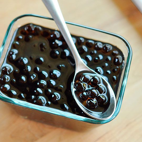 a glass bowl filled with blueberries on top of a wooden table next to a spoon