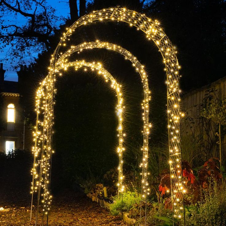 a lighted archway in the middle of a garden at night