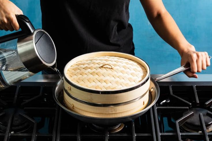 a person is cooking on the stove with a pot and pan in front of them