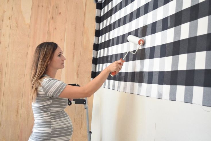 a woman is painting a wall with black and white checkered stripes on the walls