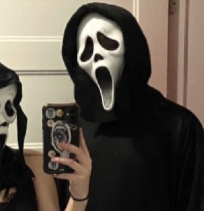 two people dressed in black and white are taking pictures with their cell phones while wearing halloween costumes