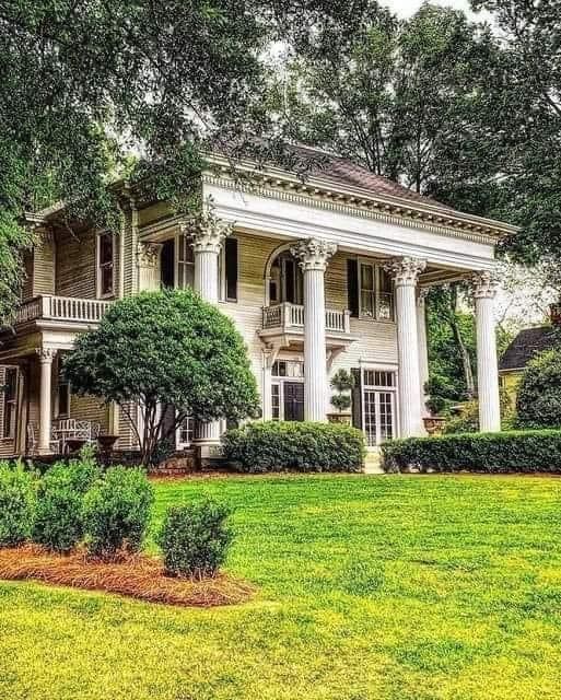 a large white house sitting on top of a lush green field