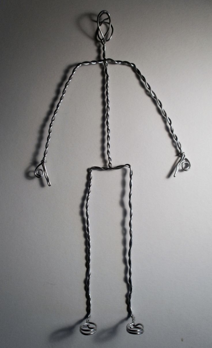 a metal wire figure is shown on a white surface with the shadow of a person's body