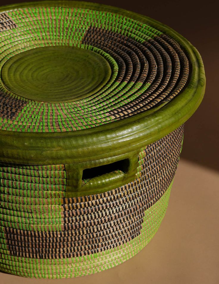 a green and brown basket sitting on top of a table