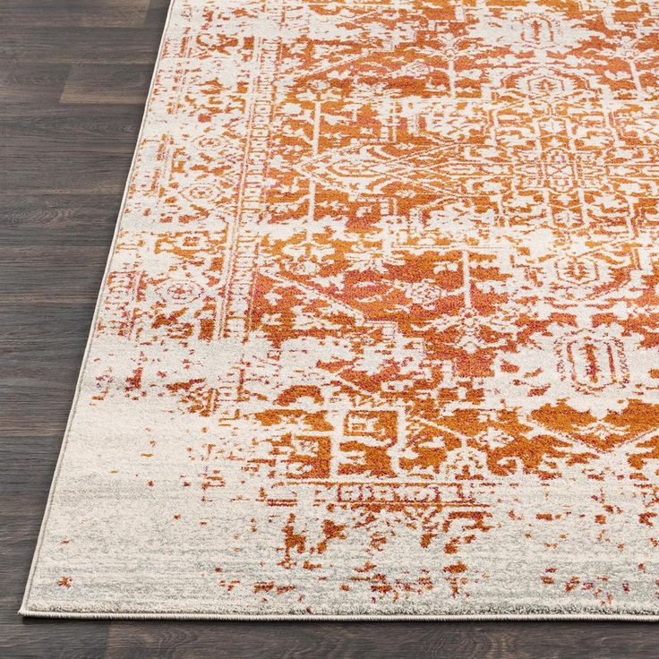 an orange and white rug on a wooden floor with dark wood floors in the background