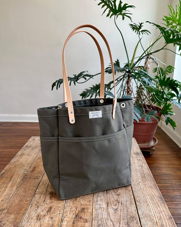 This versatile, fun tote is our best selling go-to for daily carry. Small batch handmade in our Omaha, NE studio using sturdy water repellent duck canvas and American full grain leather. WE ARE HANDMAKING MORE TOTES BUT THEY WILL NOT BE AVAILABLE UNTIL 12/20/2024. PLEASE USE OUR "NOTIFY ME" FEATURE (BELOW), AS WE'LL BE UPDATING THE SITE PERIODICALLY. ALSO, CONSIDER A GIFT CARD! Everyday Duck Canvas Bag With Pockets, Everyday Coated Canvas Bag With Reinforced Handles, Casual Duck Canvas Bag For Everyday Use, Duck Canvas Bag With Reinforced Handles For Daily Use, Coated Canvas Bag With Reinforced Handles For Everyday Use, Waxed Canvas Bag With Leather Handles For On-the-go, Everyday Canvas Bag With Duck Canvas Lining, Duck Canvas Tote Bag With Canvas Lining, Daily Use Shoulder Bag With Duck Canvas