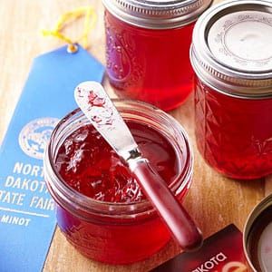 three jars filled with jam sitting on top of a wooden table next to a passport