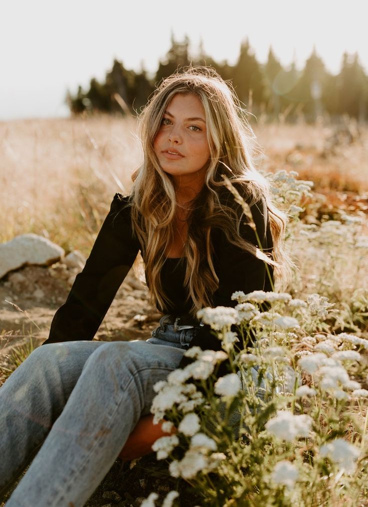 a woman sitting on the ground in a field