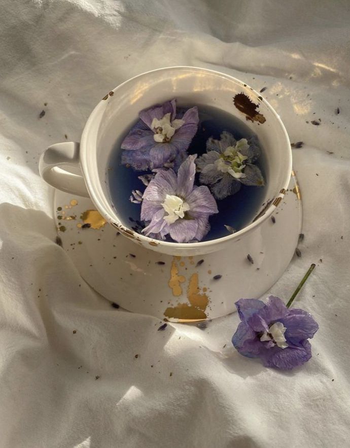 a white cup filled with water and purple flowers