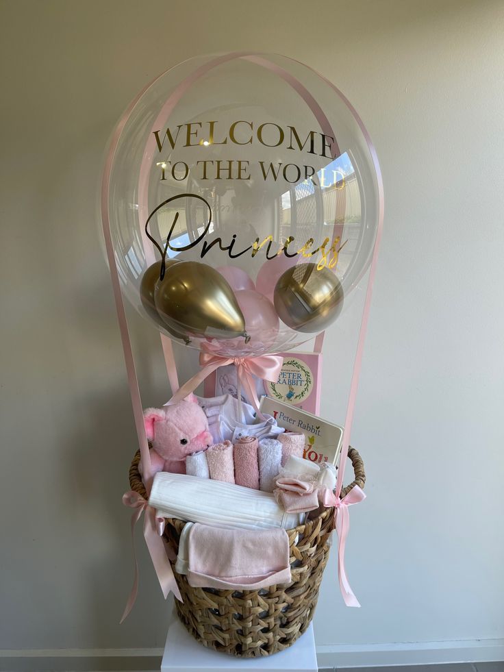 a welcome to the world gift basket with teddy bears and other baby items in it