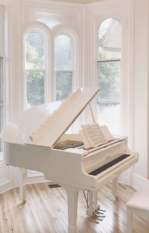 a white grand piano sitting in front of a window