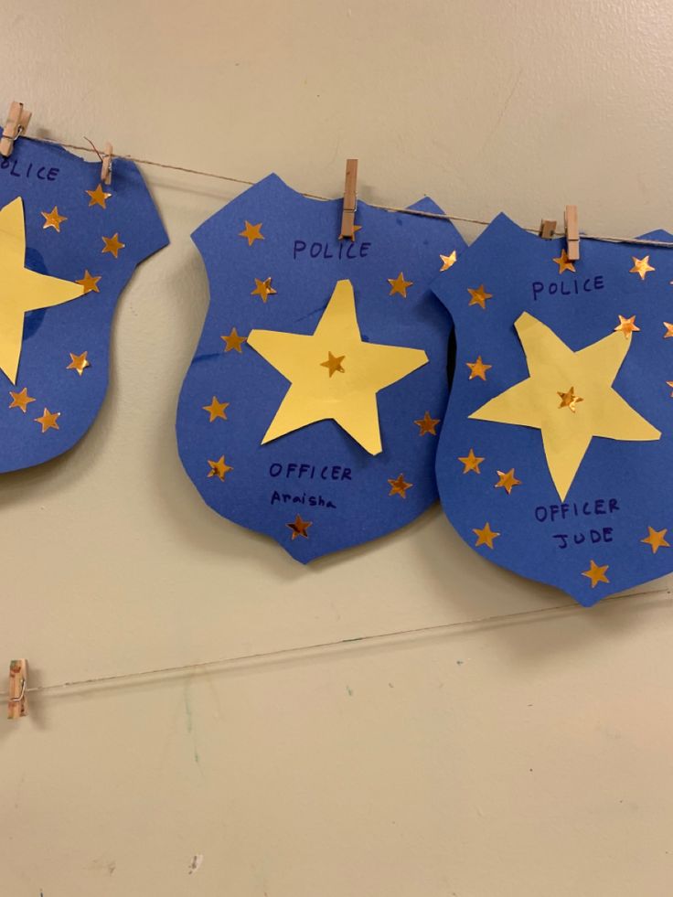 three police badges with stars on them hanging from clothes pins