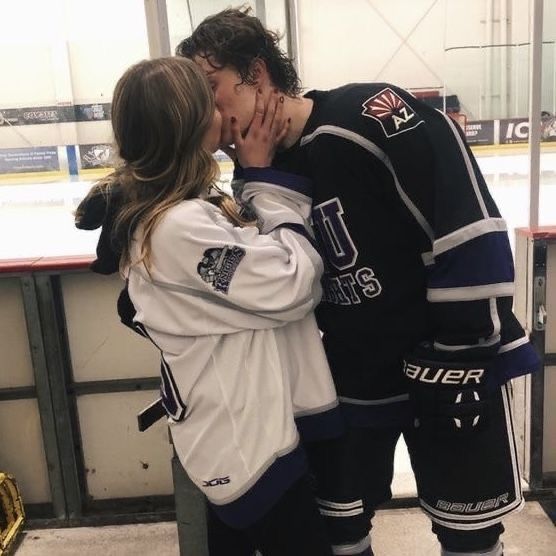 a man and woman kissing in front of an ice rink