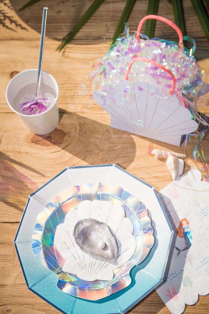 an overhead view of plates and umbrellas on a wooden table with confetti