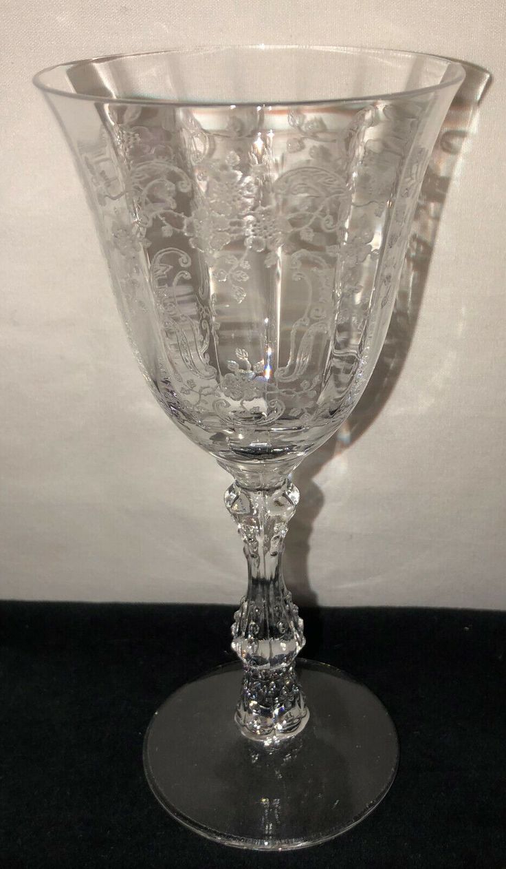 a clear glass vase sitting on top of a black tablecloth covered floor next to a white wall