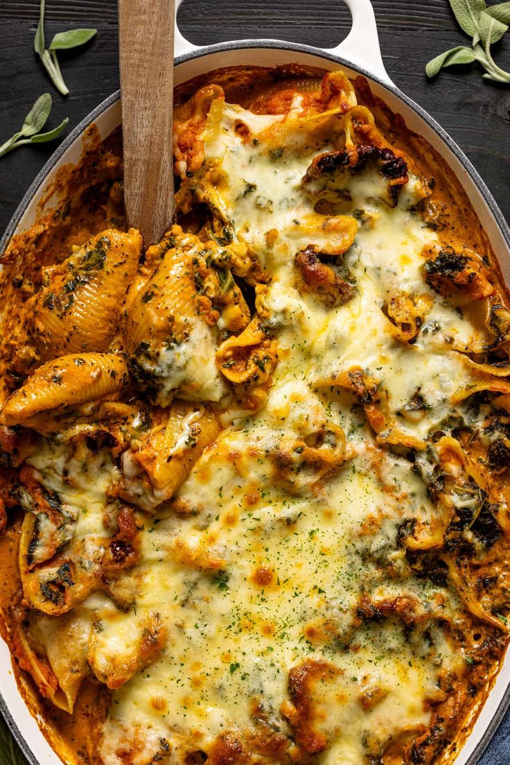 a casserole dish with chicken, cheese and spinach in it on a wooden table