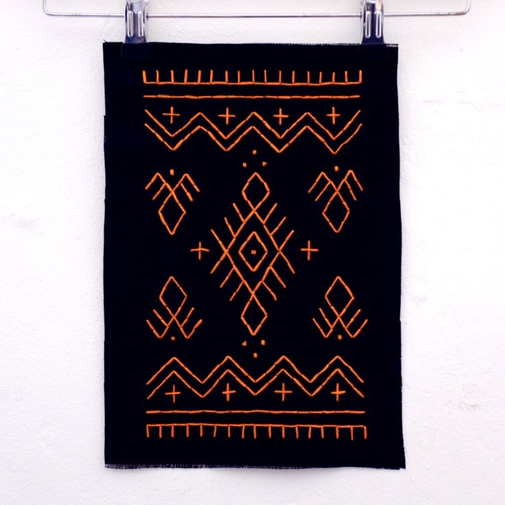 an orange and black design is hanging on a white wall