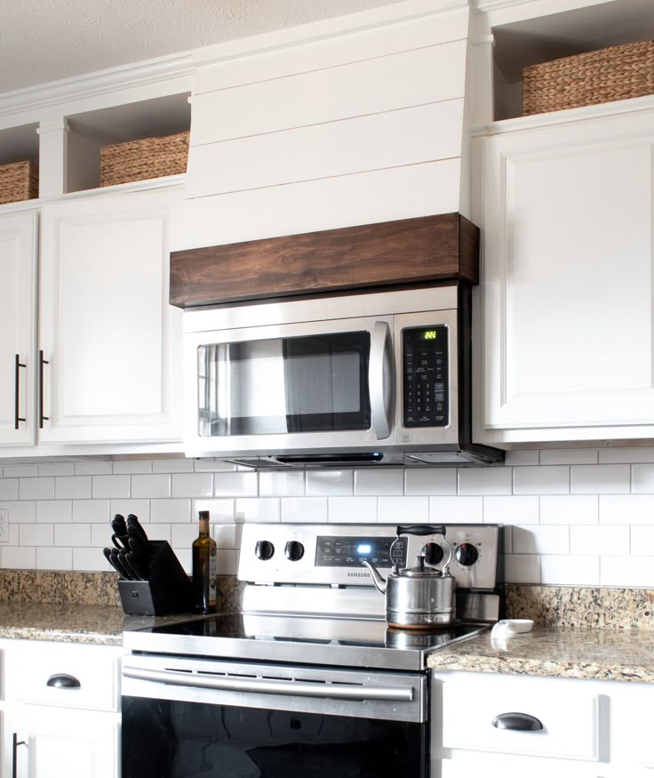 a kitchen with white cabinets and stainless steel appliances, including a microwave above the stove