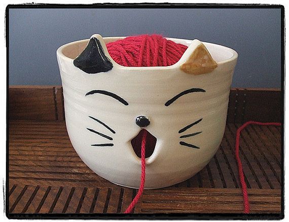 a white cat mug with red yarn in it's mouth