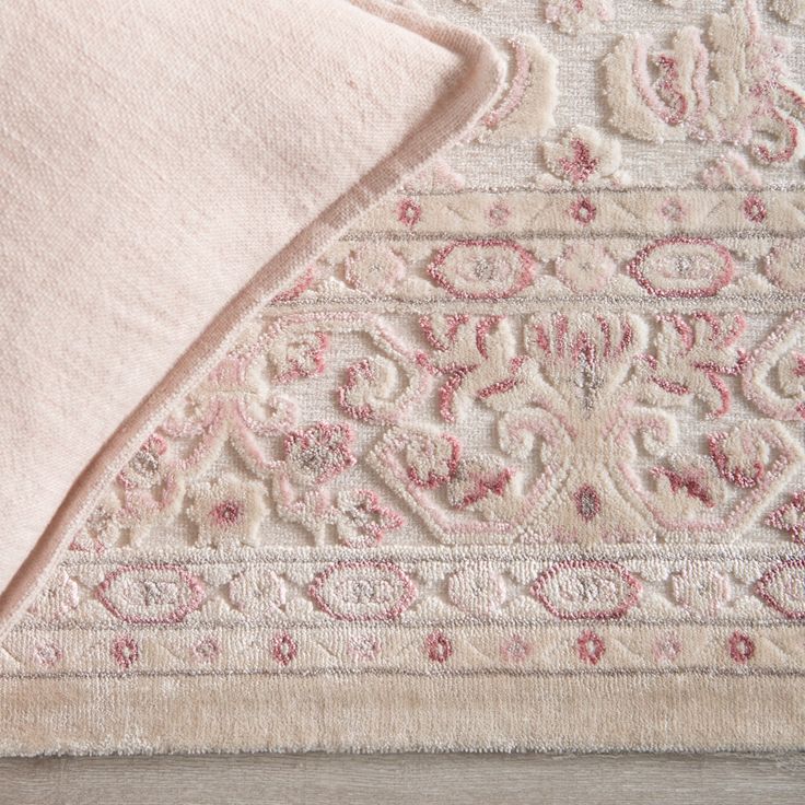 an area rug with pink and white designs on the top is laying on a wooden floor