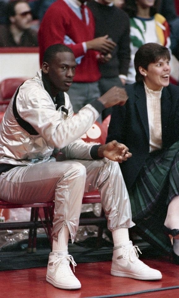 two basketball players sitting on the sidelines with their hands in each other's pockets