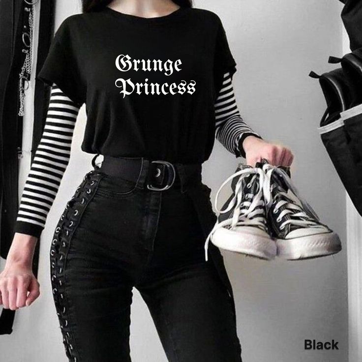 a woman wearing black and white striped shirt holding a pair of sneakers with the words grunge princess printed on it