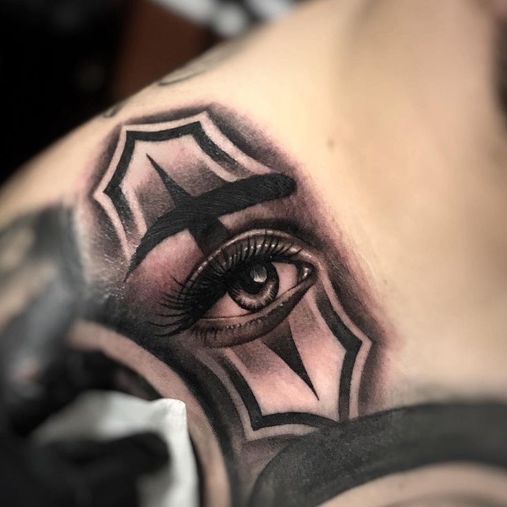 an eye tattoo on the upper half of a man's chest, with black and grey details