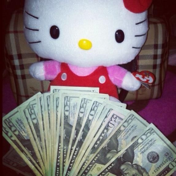 a hello kitty stuffed animal sitting on top of a pile of money next to $ 100 bills