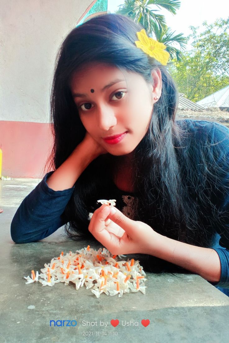 a woman sitting at a table with food in front of her and looking at the camera