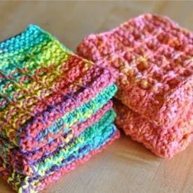 there are four pieces of colorful crocheted cloths on the table, and one is folded up